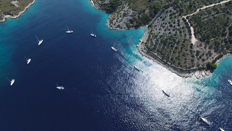 Arial view of boats in a line in a bay.